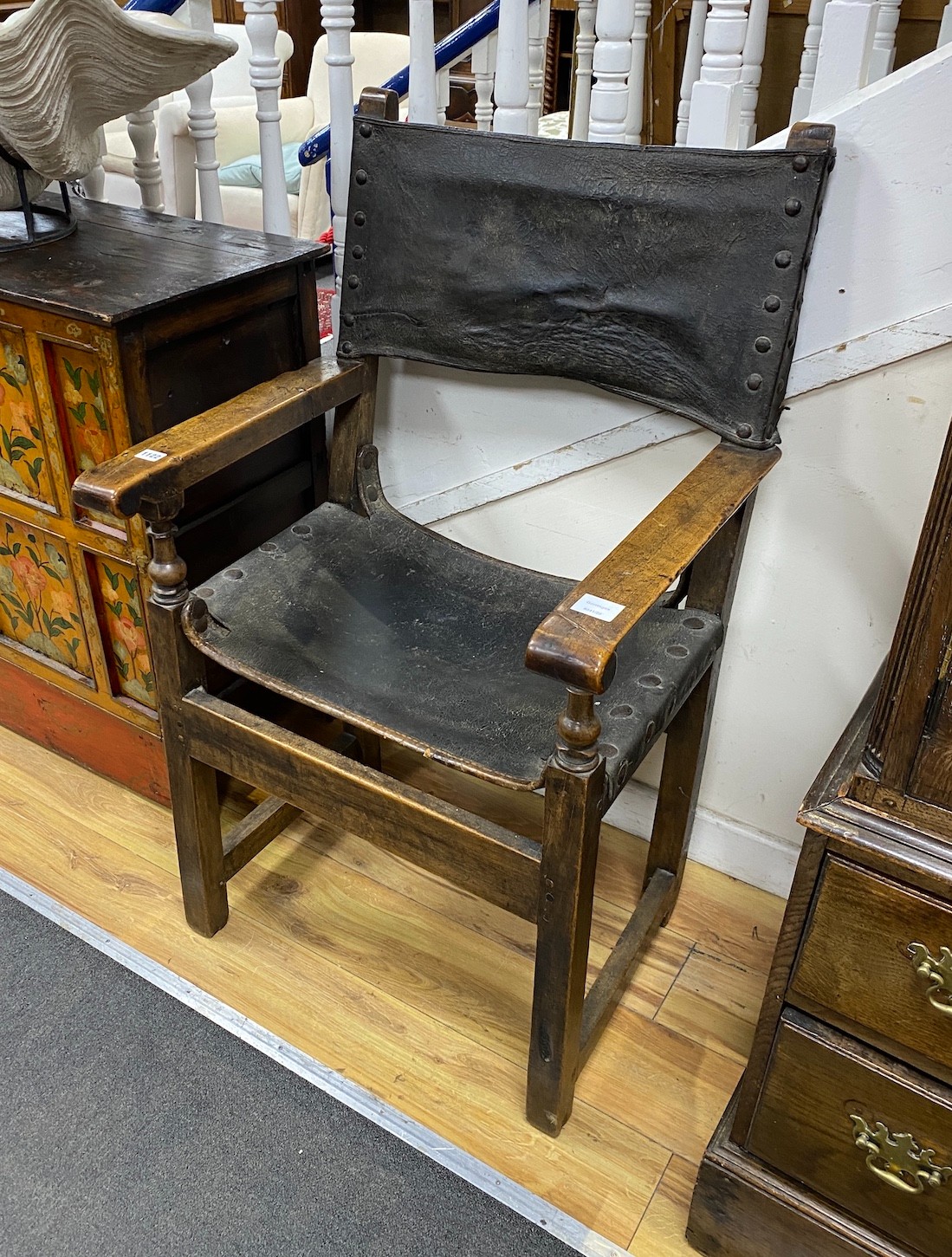 A late 17th century Italian walnut elbow chair, with a brass studded leather seat and back, width 67cm, depth 41cm, height 111cm, Provenance: Gorringe’s Jevington Place contents auction, 30th July, 1986